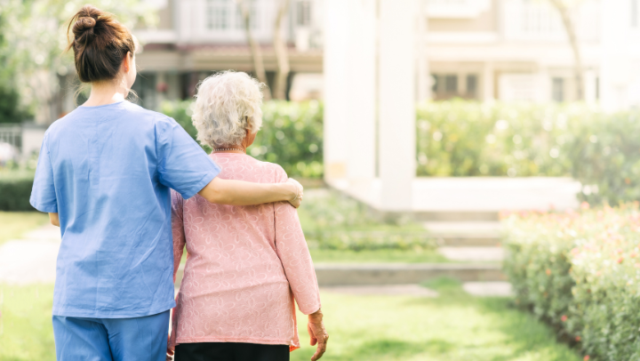 an old lady and her caregiver walking outside