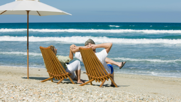 an elderly couple lying on a sunbed looking at the sea 