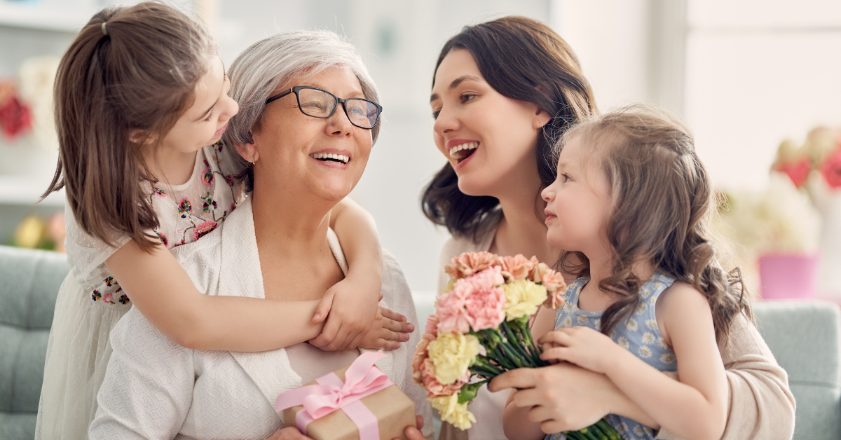 Daughter and grandchildren giving her mother a gift and flowers