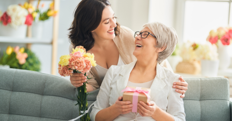 Daughter giving her mother a gift and flowers