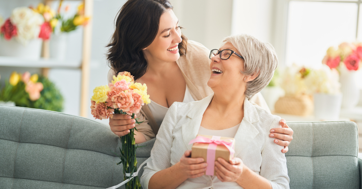 Daughter giving her mother a gift and flowers