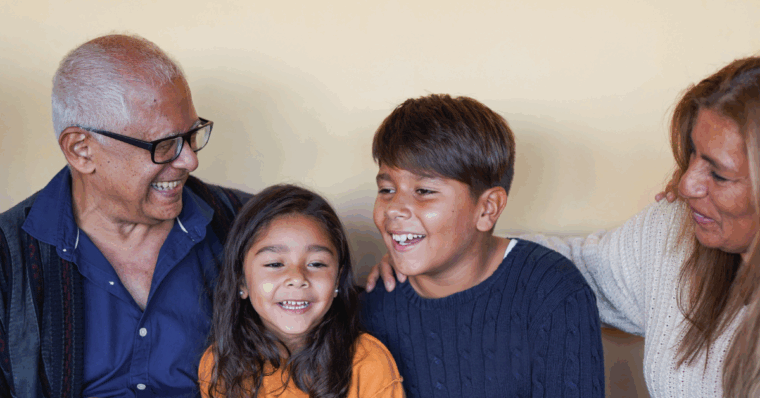 an elderly couple smiling with their grandchildren